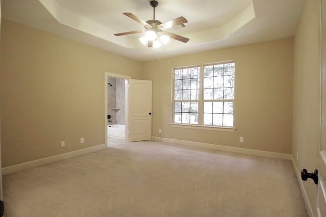 unfurnished room with ceiling fan, a raised ceiling, and carpet