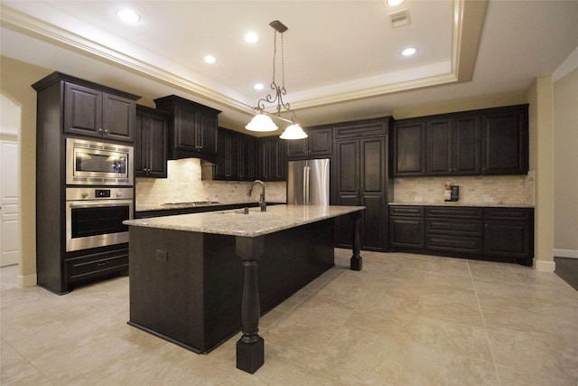 kitchen with light stone countertops, appliances with stainless steel finishes, a tray ceiling, backsplash, and pendant lighting