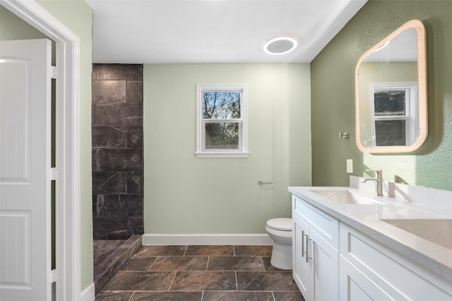 bathroom with a tile shower, toilet, and vanity