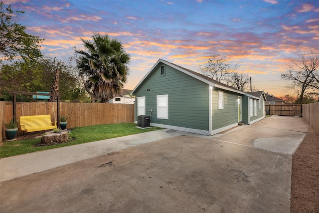 back house at dusk featuring central AC unit and a patio area