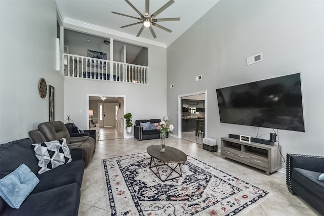 living room with crown molding, ceiling fan, a towering ceiling, and light tile floors