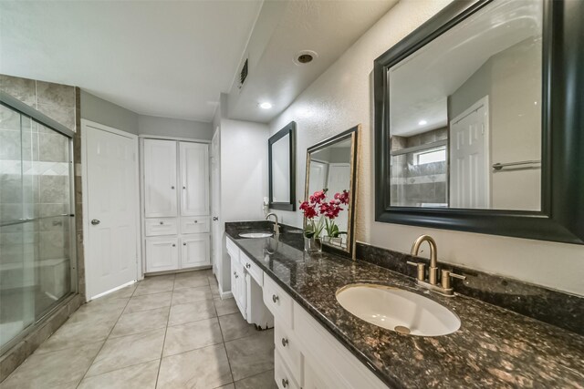 bathroom with a shower with door, tile floors, large vanity, and double sink