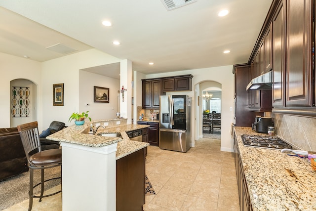 kitchen featuring stainless steel appliances, a kitchen breakfast bar, tasteful backsplash, and a kitchen island with sink