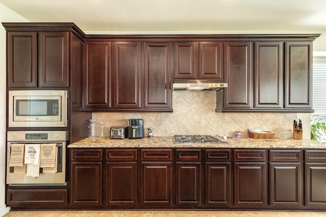 kitchen featuring appliances with stainless steel finishes, tasteful backsplash, and light stone counters