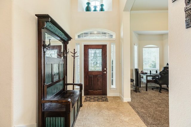 carpeted foyer featuring a high ceiling and crown molding