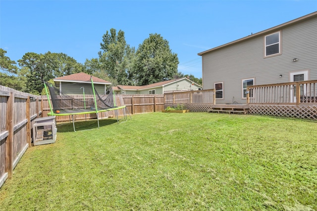 view of yard with a trampoline and a wooden deck