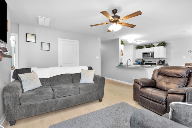 living room featuring ceiling fan, light hardwood / wood-style floors, and sink