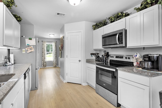 kitchen featuring white cabinets, appliances with stainless steel finishes, light stone countertops, and light hardwood / wood-style floors