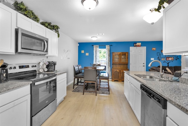 kitchen with light wood-type flooring, stainless steel appliances, white cabinetry, and sink