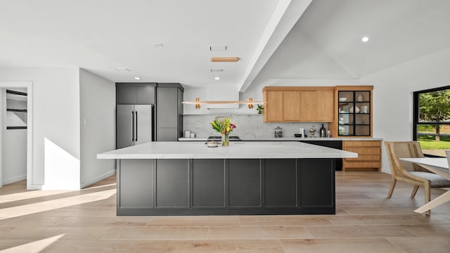 kitchen with a center island with sink, decorative backsplash, light stone counters, and high end refrigerator