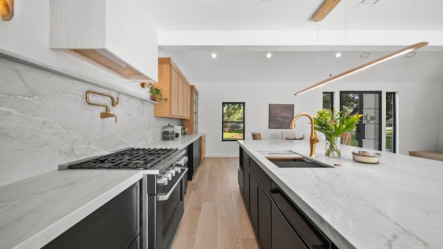 kitchen featuring high end range, sink, light hardwood / wood-style flooring, decorative backsplash, and light brown cabinetry