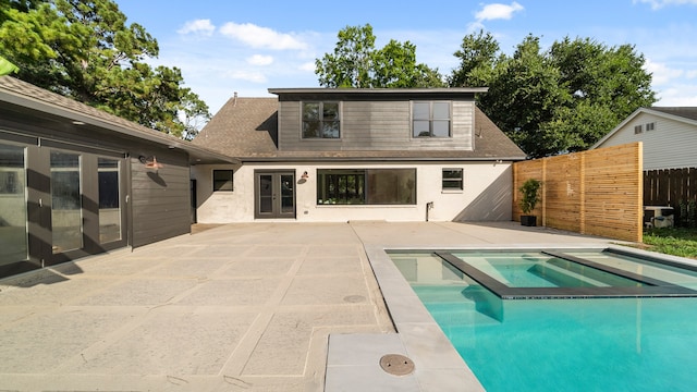 rear view of house with a patio area, a swimming pool with hot tub, and french doors