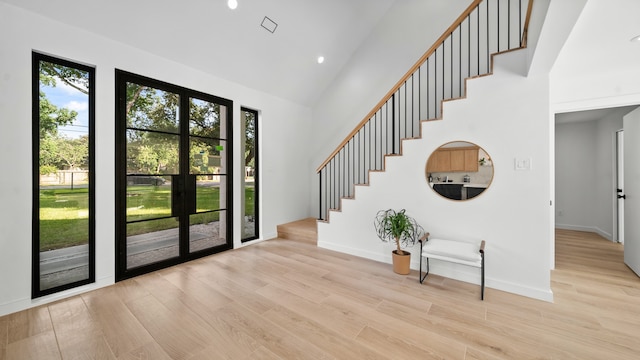 foyer with high vaulted ceiling and light wood-type flooring