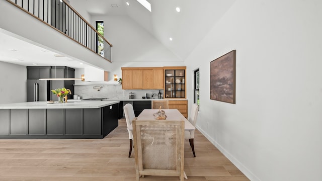 kitchen featuring light brown cabinets, light wood-type flooring, high vaulted ceiling, and high end refrigerator