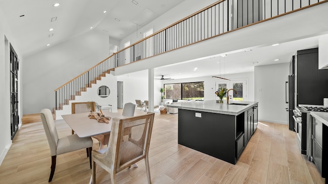 dining space featuring light hardwood / wood-style flooring, high vaulted ceiling, ceiling fan, and sink