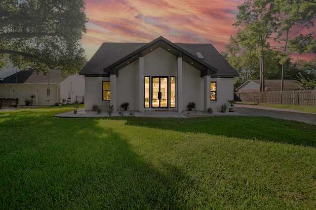 back house at dusk with french doors and a lawn