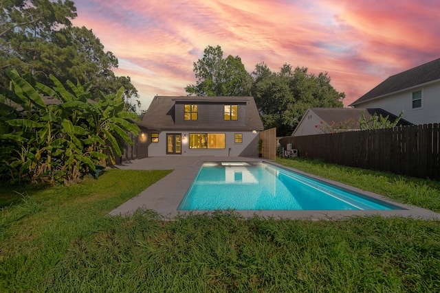 back house at dusk featuring a fenced in pool, a yard, and a patio