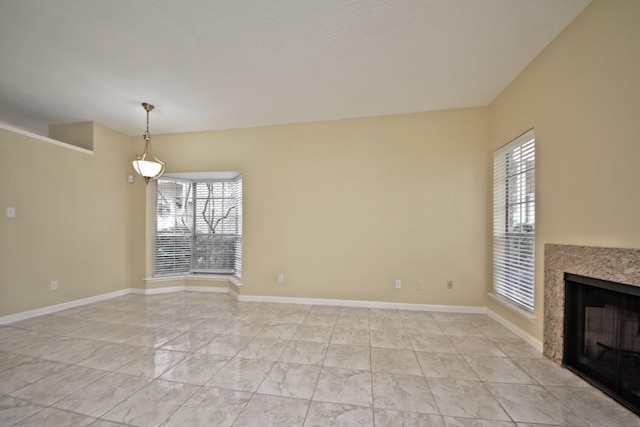 unfurnished living room featuring a premium fireplace, plenty of natural light, and light tile flooring