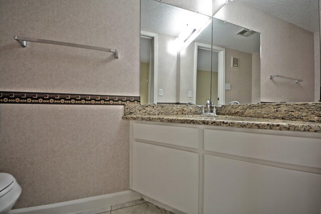 bathroom with vanity with extensive cabinet space, toilet, and tile floors