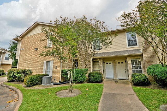 view of front of property with a front yard and central air condition unit