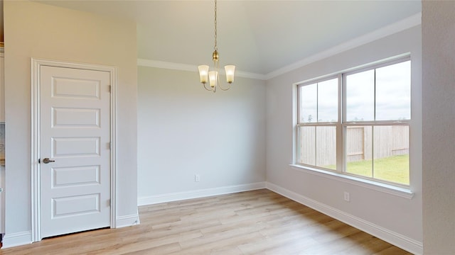 empty room with a notable chandelier, crown molding, and light hardwood / wood-style flooring