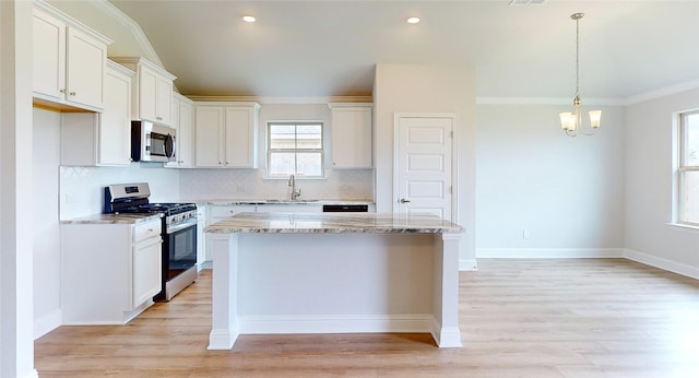 kitchen featuring a center island, light stone countertops, light hardwood / wood-style flooring, appliances with stainless steel finishes, and white cabinets