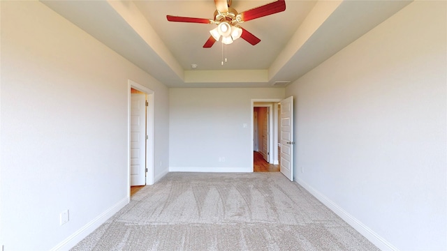 unfurnished room featuring ceiling fan, carpet, and a tray ceiling