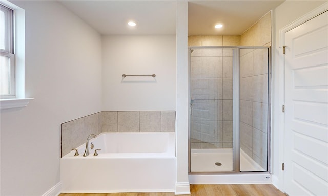 bathroom with a healthy amount of sunlight, hardwood / wood-style flooring, and plus walk in shower