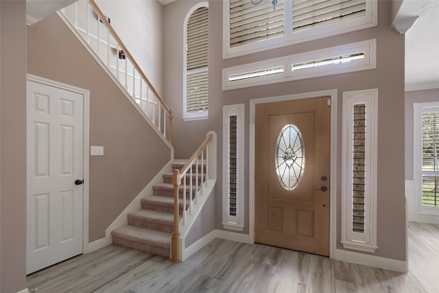 entryway featuring a towering ceiling, light hardwood / wood-style flooring, and crown molding