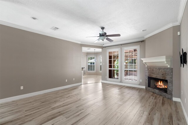 unfurnished living room featuring crown molding, a textured ceiling, light wood-type flooring, a stone fireplace, and ceiling fan