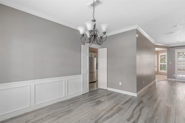 unfurnished dining area featuring a chandelier, light wood-type flooring, and ornamental molding