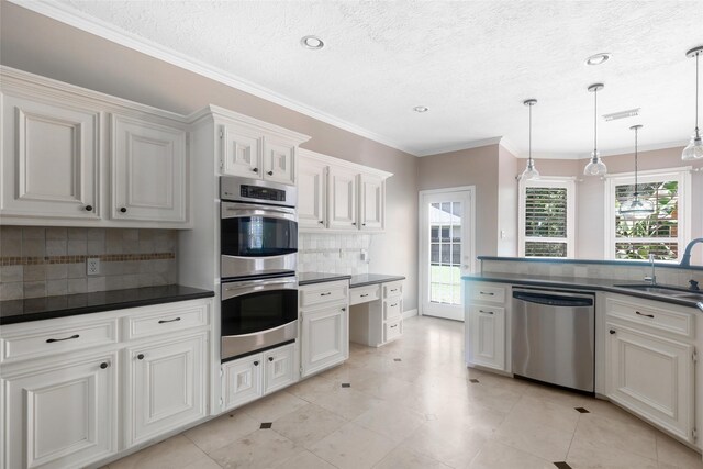 kitchen featuring stainless steel appliances, backsplash, hanging light fixtures, ornamental molding, and white cabinets