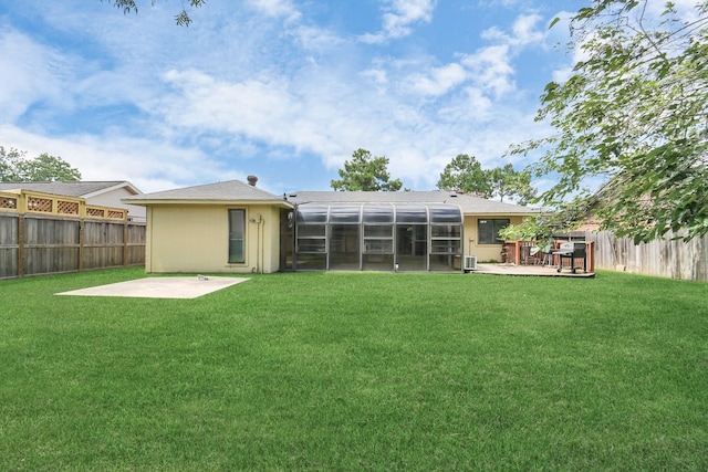 rear view of property featuring a lawn, glass enclosure, and a patio