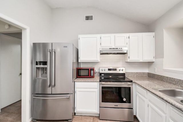 kitchen featuring vaulted ceiling, decorative backsplash, appliances with stainless steel finishes, light tile patterned flooring, and white cabinetry