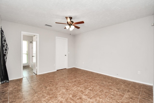 unfurnished room with ceiling fan and a textured ceiling