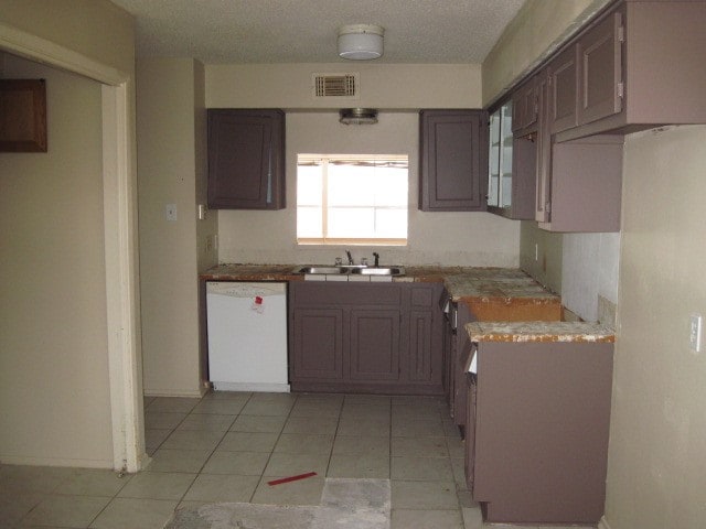 kitchen featuring dark brown cabinetry, sink, white dishwasher, and light tile floors