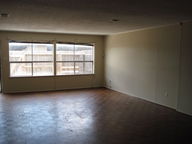 unfurnished room featuring plenty of natural light, a textured ceiling, and parquet floors