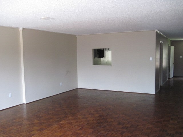 empty room featuring dark parquet floors and a textured ceiling