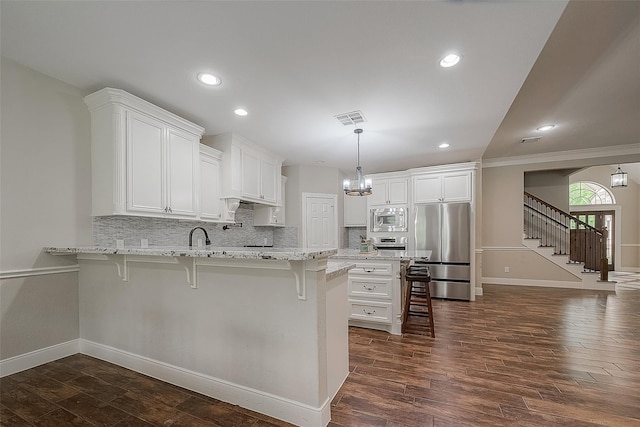 kitchen with tasteful backsplash, a breakfast bar, stainless steel appliances, dark wood-type flooring, and white cabinetry