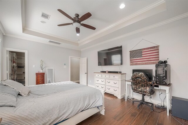 bedroom with ceiling fan, a raised ceiling, a walk in closet, and dark wood-type flooring