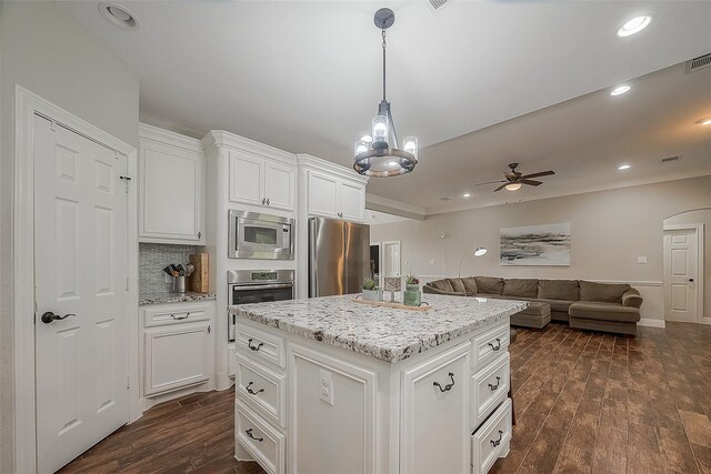 kitchen with appliances with stainless steel finishes, a center island, white cabinetry, and dark wood-type flooring