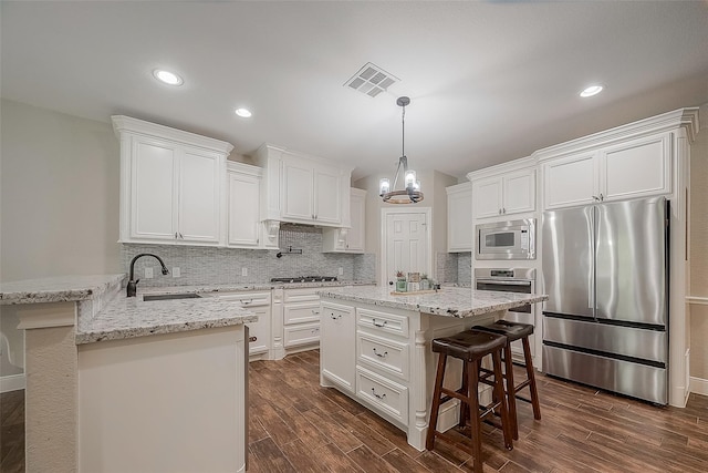 kitchen featuring sink, stainless steel appliances, dark hardwood / wood-style floors, a kitchen bar, and white cabinets