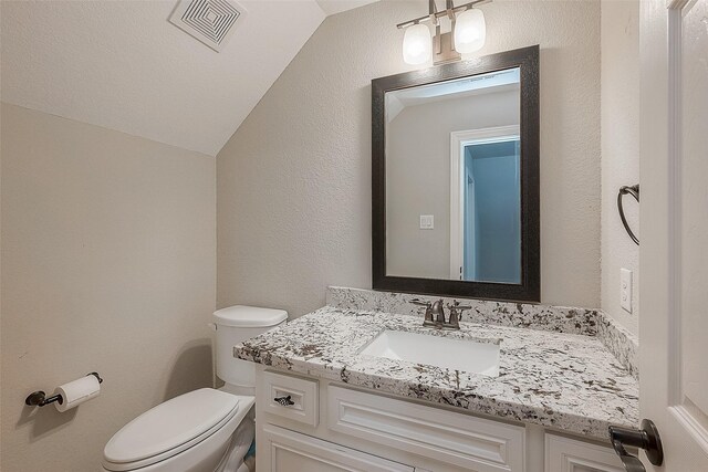 bathroom with vanity, toilet, and lofted ceiling