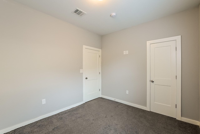 spare room with dark colored carpet