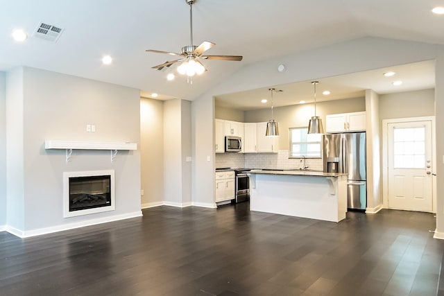 kitchen with white cabinetry, a kitchen bar, stainless steel appliances, lofted ceiling, and hanging light fixtures