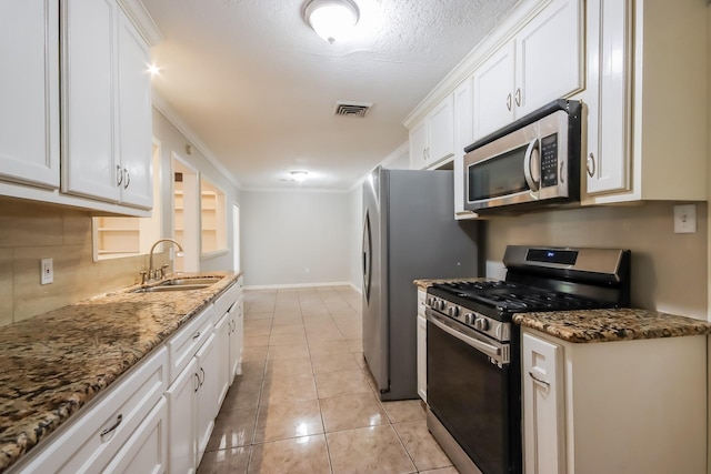 kitchen featuring dark stone counters, sink, ornamental molding, white cabinetry, and stainless steel appliances