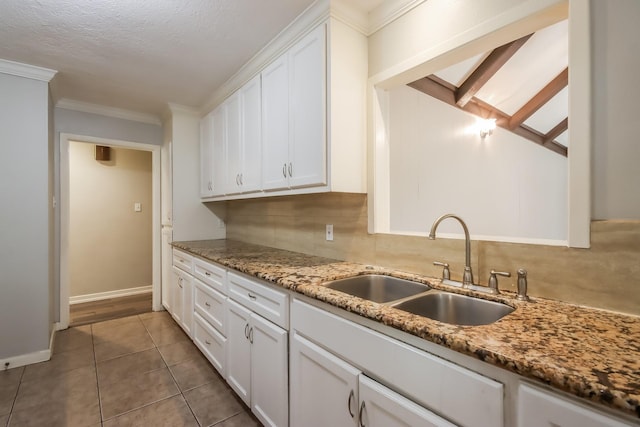 kitchen with light stone countertops, sink, white cabinets, and ornamental molding