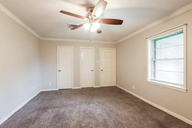 unfurnished bedroom featuring carpet flooring, crown molding, ceiling fan, and multiple closets