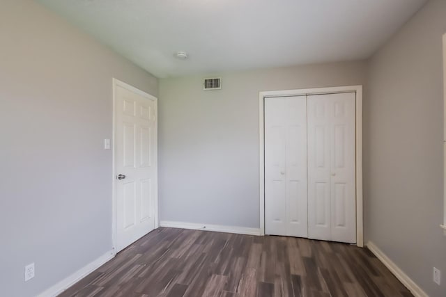 unfurnished bedroom with dark hardwood / wood-style flooring and a closet