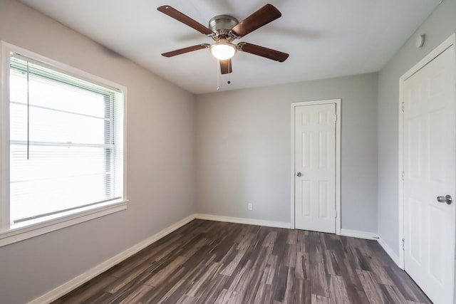 unfurnished bedroom with multiple windows, ceiling fan, and dark wood-type flooring